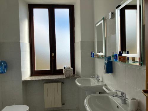 a bathroom with two sinks and a toilet and a window at Camere Villa Lunardini in Frassinetto