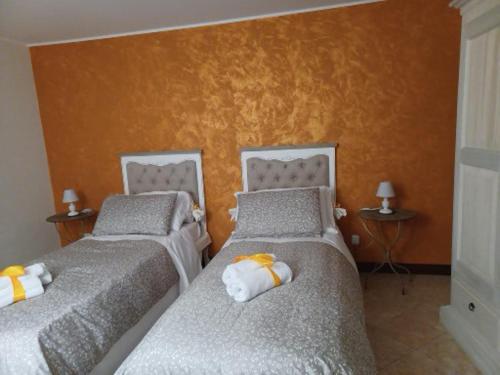 two beds in a room with orange walls at B&B Casa del Teatro in Mantova