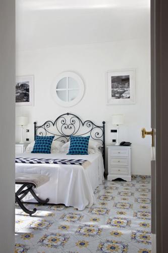 a white bedroom with a bed with blue pillows at Hotel Canasta in Capri
