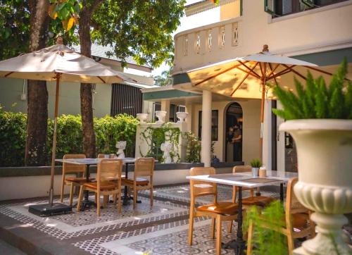 an outdoor patio with tables and chairs and umbrellas at Sann Hotel in Chiang Rai