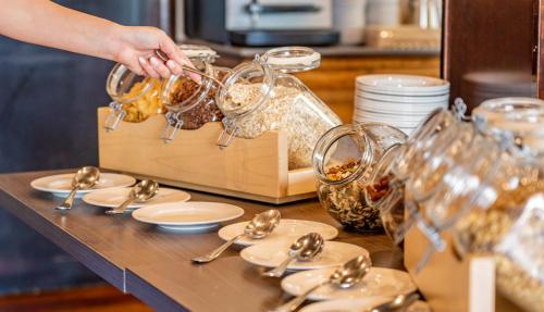 Iemand schept eten in schalen op een tafel. bij Apartahotel Suites Vila Birdie in Navata