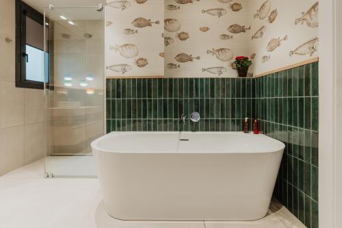 a white tub in a bathroom with green tiles at Petit Luxe Volta ÀTIC in Terrassa