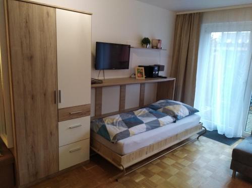 een slaapkamer met een bed en een kast met een televisie bij Ferienwohnung Leinetal in Elze