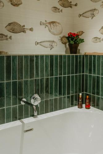 a bathroom with a green tiled wall and a bath tub at Petit Luxe Volta ÀTIC in Terrassa