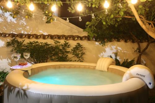 una bañera de hidromasaje en un jardín con una mesa y copas de vino en A Janela Do Castelo, en Monsaraz