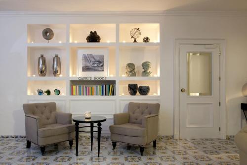 a room with two chairs and a table and shelves with vases at Hotel Canasta in Capri