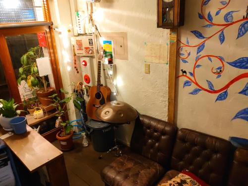 a living room with a leather couch and a guitar at Guest House mii in Osaka