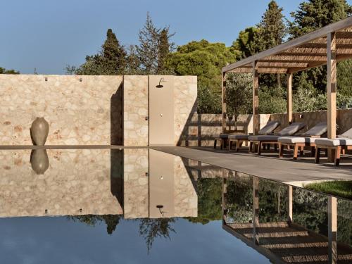 a pool of water with chairs and a pavilion at Cielo villas - An Authentic Mediterranean Living in Zakynthos Town