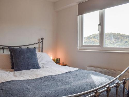 1 dormitorio con 1 cama con manta azul y ventana en Vine Cottage, en Crich