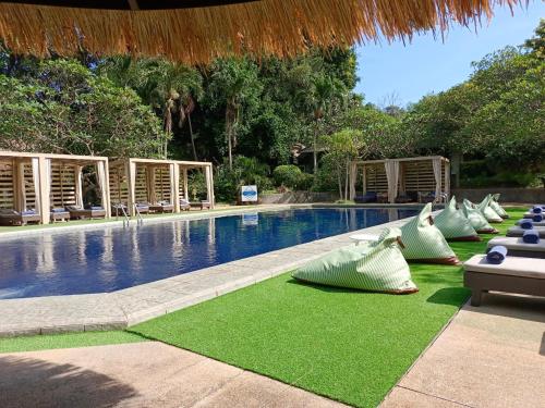 een zwembad met ligstoelen en stoelen naast een resort bij Let's Hyde Pattaya Resort & Villas - Pool Cabanas in Noord Pattaya