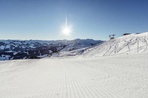 a snow covered slope with the sun in the background at Ferienwohnung Aschaber in Wildschönau