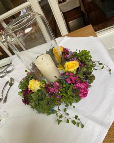 a candle in a bouquet of flowers on a table at Hotel Pilgrimhaus in Soest