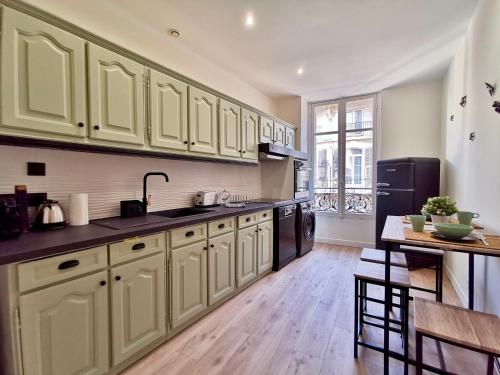 une grande cuisine avec des placards verts et une table dans l'établissement Le LORRAINE, à Nice