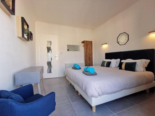 une chambre avec un grand lit et une chaise bleue dans l'établissement Le SAINT PIERRE, à Nice