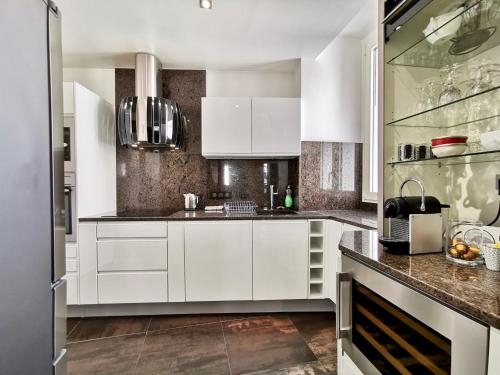 - une cuisine avec des placards blancs et des comptoirs en marbre dans l'établissement LUXURY BAQUIS, à Nice