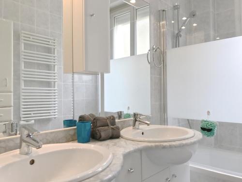 a white bathroom with two sinks and a mirror at Appartement 'le Fontainebleau' in Nice