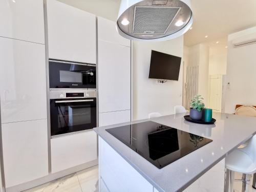 une cuisine avec des armoires blanches et un comptoir dans l'établissement Le MASSENET by Booking Guys, à Nice