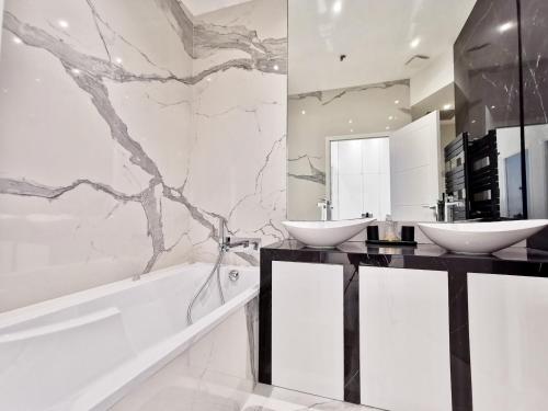 une salle de bain avec deux lavabos et une baignoire dans l'établissement Le MASSENET by Booking Guys, à Nice