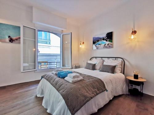 une chambre avec un grand lit et une grande fenêtre dans l'établissement STUDIO PETIT OPERA, à Nice