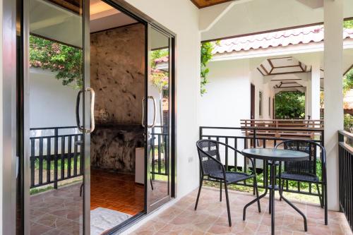 a glass door leading to a patio with a table and chairs at El Matcha Lanta Resort in Phra Ae beach