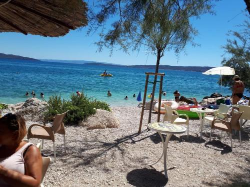a group of people sitting on a beach near the water at Apartman Laura in Kaštela