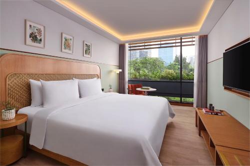 a bedroom with a large white bed and a large window at ARTOTEL Casa Kuningan in Jakarta