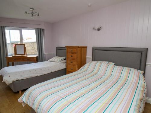 a bedroom with two beds and a dresser and a window at 1 St Marys Court in Tenby