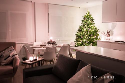 a living room with a christmas tree and a dining table at Lujoso apartamento entre 2 playas con garaje, wifi in Gijón