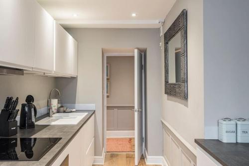 a kitchen with white cabinets and a sink at Nelson Crescent East : Modern one bedroom basement apartment in central location in Kent