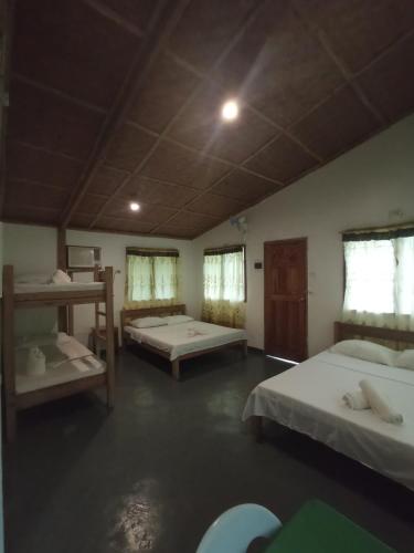 a room with two beds and two windows at Tori's Backpacker's Paradise in Siquijor