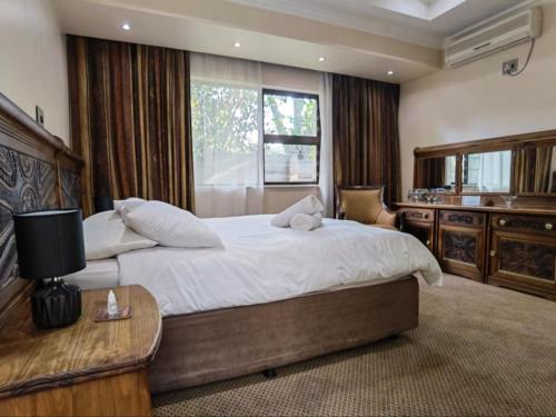 1 dormitorio grande con 1 cama grande y ventana en Orchids Lodge, en Fourways