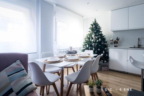 a living room with a table and chairs and a christmas tree at Lujoso apartamento entre 2 playas con garaje, wifi in Gijón