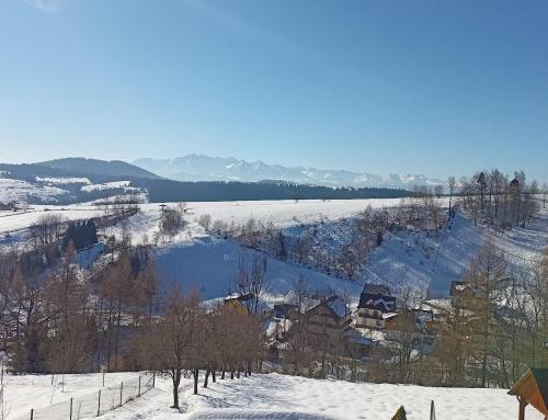 a view of a snow covered valley with a lake at Domek u Stolarza in Grywałd