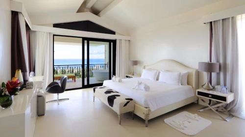 sypialnia z dużym białym łóżkiem i balkonem w obiekcie Navy Hill Resort w Garapan