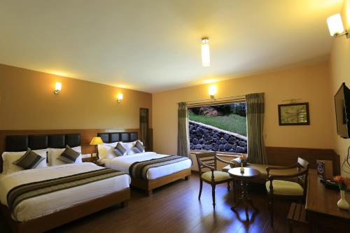 a hotel room with two beds and a table at Western Valley Resorts Ooty in Ooty