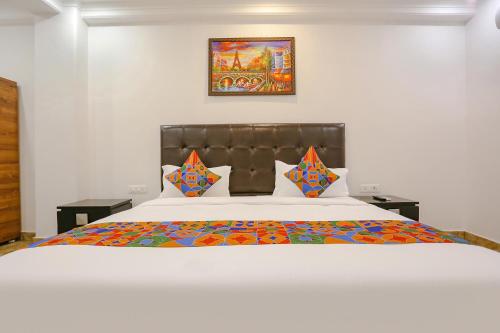 a bedroom with a large white bed with colorful pillows at FabExpress Taj Residency - Nr Yashobhoomi Convention Centre in New Delhi