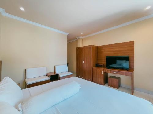 a bedroom with a white bed and a television at Urbanview My Home One Gili Trawangan in Gili Trawangan