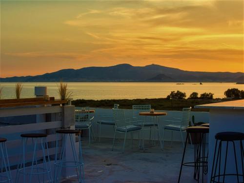 a patio with chairs and tables and a view of the water at Studios Vrettos Beachfront Hotel in Plaka