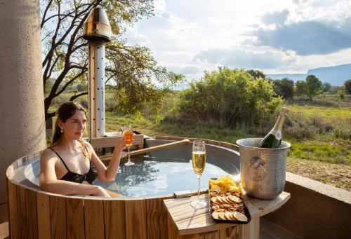 Una donna in una vasca idromassaggio con un bicchiere di vino di Sofala Lodge a Mokopane