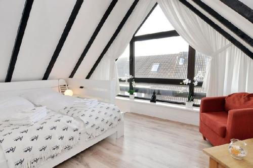 ein Schlafzimmer mit einem Bett, einem Stuhl und einem Fenster in der Unterkunft Wohnung Sylter Brise in Wenningstedt-Braderup