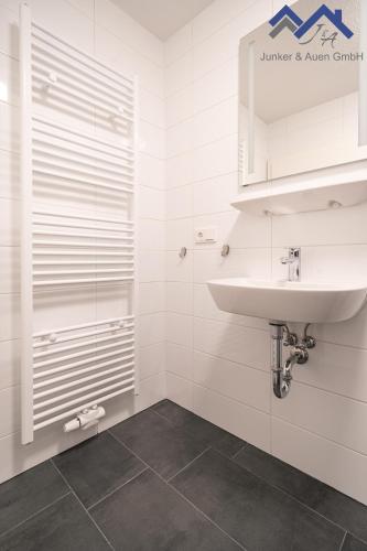 a white bathroom with a sink and a shower at Ferienapartments Junker & Auen in Weener