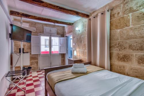 um pequeno quarto com uma cama num quarto em Augustinian em Valletta