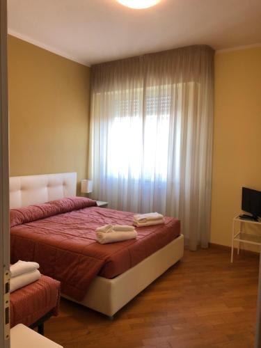 a bedroom with a bed with red sheets and a window at Appartamento Vaniglia in Viareggio