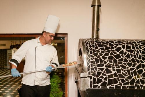 a man in a chefs hat is putting a pizza at 8fold by LaRiSa in Shimla