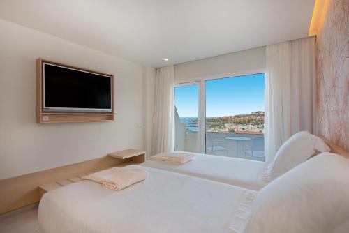 a white bedroom with a large window and a tv at Iberostar Selection Sábila - Adults Only in Adeje