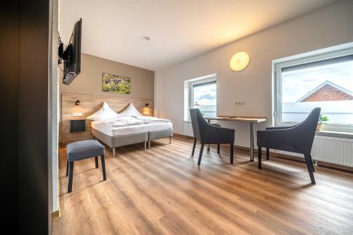 ein Hotelzimmer mit einem Bett, einem Tisch und Stühlen in der Unterkunft Ferienapartments Junker & Auen in Weener