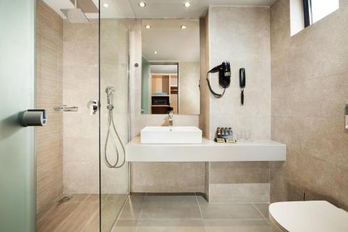 a bathroom with a sink and a shower at Porto Bello Beach Hotel in Kardamaina