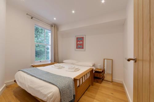 a bedroom with a bed with white sheets and a window at Bright Beautiful Modern 2 Bed Home Pass The Keys in Cambridge