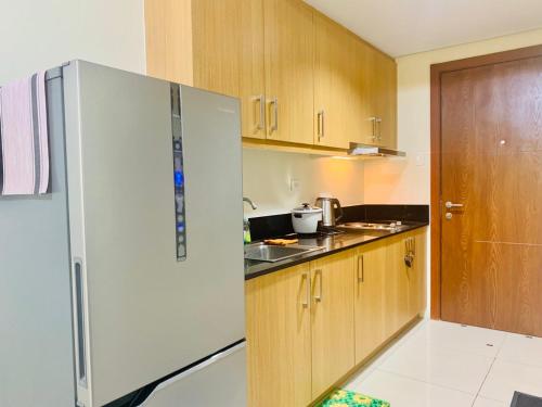 uma cozinha com um frigorífico branco e armários de madeira em Sea Residences - Call Ang Alano em Manila