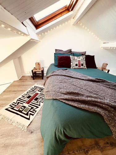 une chambre avec un lit vert et une lucarne dans l'établissement Le petit nid perché sous les toits, vue mer, au Havre